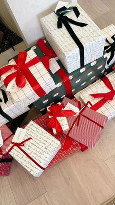 several wrapped presents sitting on the floor with red and white ribbons tied around each box