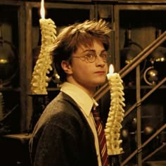 a young man wearing glasses and a tie holding a candle in front of his head