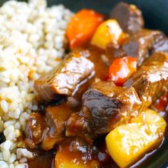 a close up of a plate of food with rice and meat in sauce on it