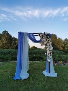 a blue and white wedding arch with flowers on the top is set up for an outdoor ceremony