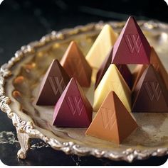 four pyramids are sitting on a plate and one is gold, the other is red