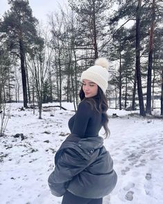 a pregnant woman standing in the snow with her hands on her hips and looking at the camera