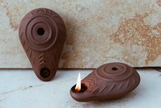 two brown candles sitting next to each other on top of a white tile countertop