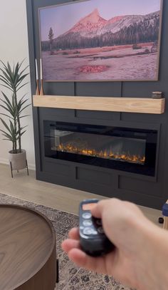 a person holding a remote control in front of a fireplace