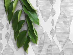 green leaves are hanging on the wall next to a white and gray patterned wallpaper