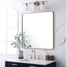 a bathroom vanity with a large mirror above it and gold faucets on the sink