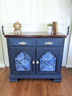 a blue cabinet with flowers painted on the front and sides, sitting on a hard wood floor