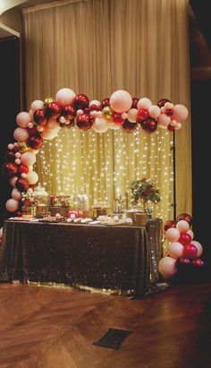 a table topped with lots of balloons next to a wall covered in stars and lights