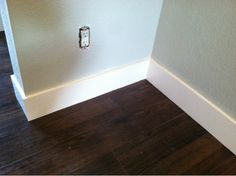 an electrical outlet in the corner of a room with hard wood floors and white walls