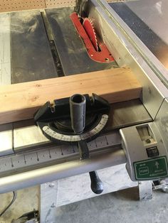 a machine that is cutting wood with a ruler on the table next to it's blades