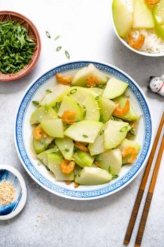 a bowl filled with food next to chopsticks and bowls full of rice, carrots and apples