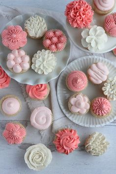 some cupcakes are sitting on plates with pink frosting and white icing