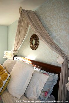 a bed with four pillows on top of it and a canopy over the headboard