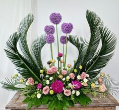 an arrangement of flowers and greenery on a table