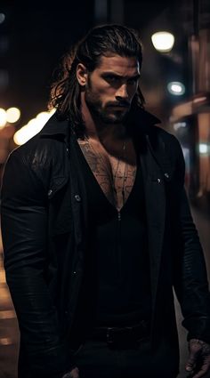 a man with long hair standing in the street at night wearing a black jacket and jeans