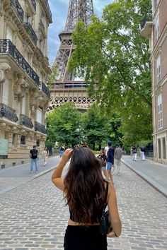 a woman taking a photo of the eiffel tower from an alleyway in paris