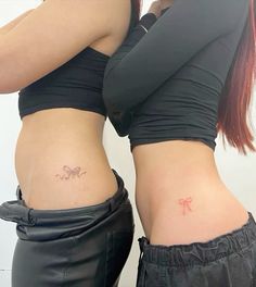 two women with tattoos on their stomachs, one has a bow in the middle