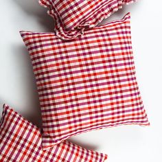 three red and white checkered pillows sitting on top of each other next to one another