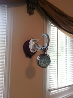 a clock mounted to the side of a wall next to a window with blind shades