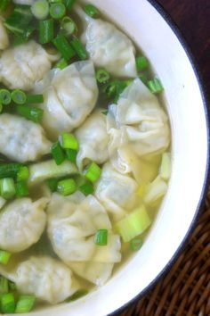 a white bowl filled with dumplings and green onions