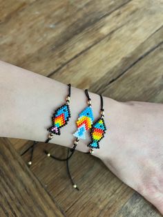 a woman's arm with two bracelets on it, one is colorful and the other is black