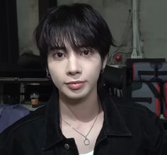 a young man with black hair and piercings on his ears looking at the camera