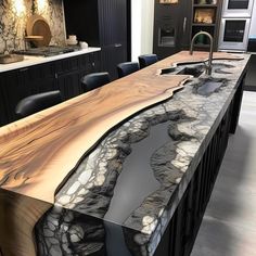 a kitchen counter with an unusual design on it's side and black chairs at the end