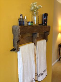 two white towels hanging on a wooden shelf in a bathroom with yellow walls and flooring