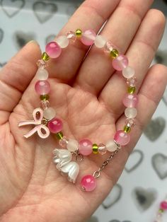 This charming bracelet features a delightful mix of pink, white, and green beads, creating a playful and feminine look.  The bracelet is accented with a cute pink bow charm and a delicate white flower charm, adding a whimsical touch to your style.  A dangling pink bead adds extra movement and charm.  Stretchy and comfortable, this bracelet is perfect for everyday wear or as a sweet gift for someone special.  Add a pop of color and fun to any outfit with this lovely accessory! **Listing is for on Pink Cute Bracelet, Pink Beads Bracelets, Charming Bracelet, Flower Charm Bracelet, Bracelets Design, Beads Bracelet Design, Green Beads, Fancy Jewelry, Sweet Gifts