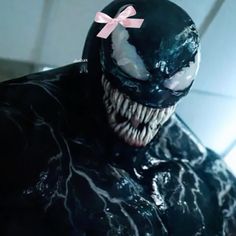 a close up of a person wearing a black suit with a pink bow on it's head