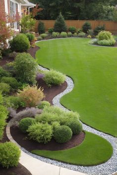 a large yard with green grass and bushes in the center, surrounded by landscaping materials