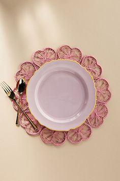 a pink plate with gold trim and two forks on it next to a white wall