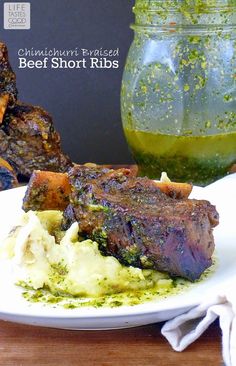 a white plate topped with meat and mashed potatoes next to a jar of pesto