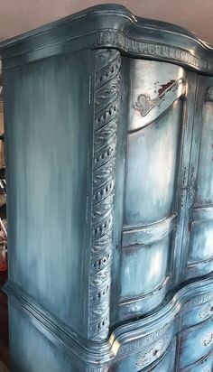 an antique blue armoire with ornate carvings on it