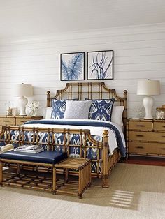 a bed with blue and white pillows in a bedroom next to two pictures on the wall