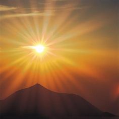 the sun is shining brightly over an island in the ocean with mountains in the background