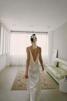 a woman in a white dress walking through a living room