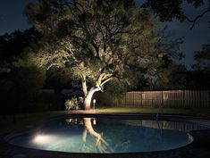 a pool at night with the lights on and trees in the back ground, lit up