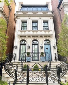 a large white house with black wrought iron railings and stairs leading up to the front door