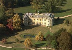 an aerial view of a large house in the middle of a lush green field with lots of trees