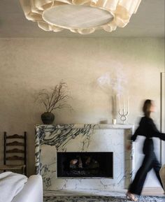 a woman walking past a fireplace in a living room