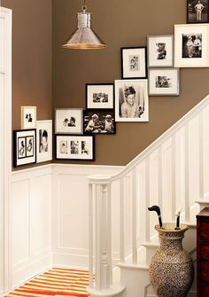 a stairway with pictures on the wall and an orange area rug underneath it that says,