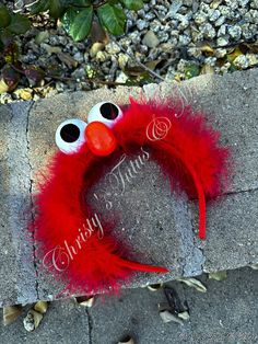 a red wreath with googly eyes and a fake bird's head on it