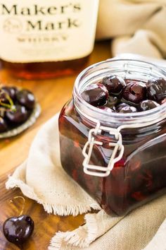 a glass jar filled with cherries sitting on top of a table