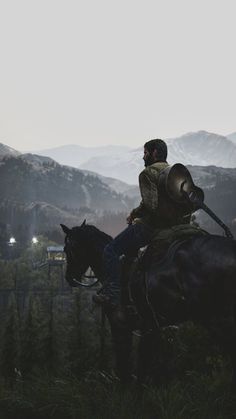 a man riding on the back of a brown horse next to a lush green hillside