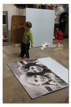 a young boy standing in front of a photo on the floor with his hands behind his head