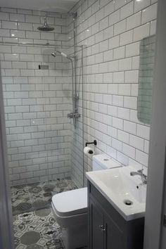 a white toilet sitting next to a bathroom sink under a shower head mounted faucet