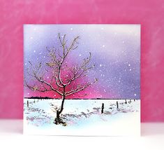 a card with a tree in the snow and purple sky behind it, on a pink background