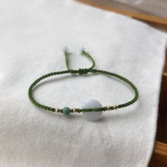 a green string bracelet with two white beads