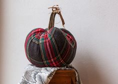 a plaid hat sitting on top of a wooden box next to a black and red pumpkin